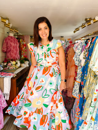 Woman wearing a colorful floral dress in a clothing store.