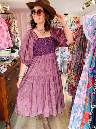 Woman wearing a plum floral dress and brown hat in a clothing store