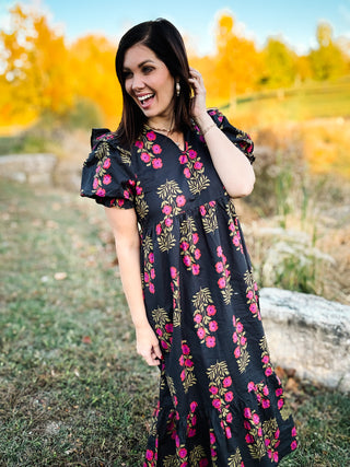 woman standing in a field wearing a black floral midi dress