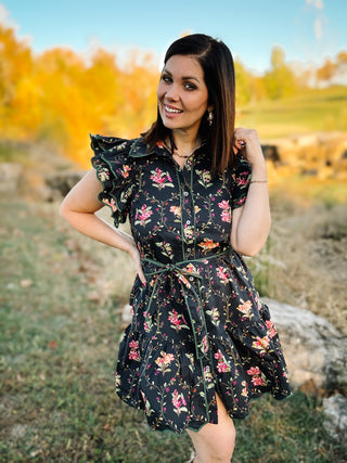 woman wearing black floral mini dress standing in an outdoor fall setting