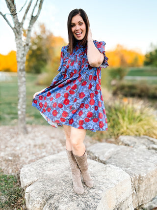 woman in a field wearing a blue and red floral dress