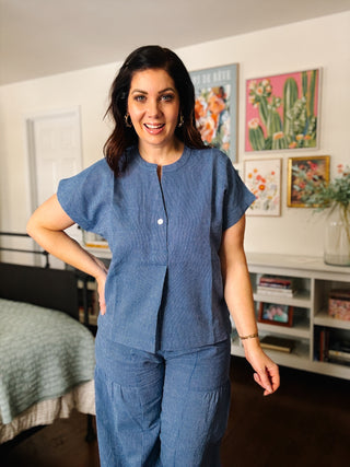 Woman wearing a blue outfit standing in a room with colorful artwork on the wall.