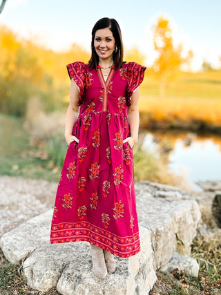 woman in a field wearing a magenta floral midi dress