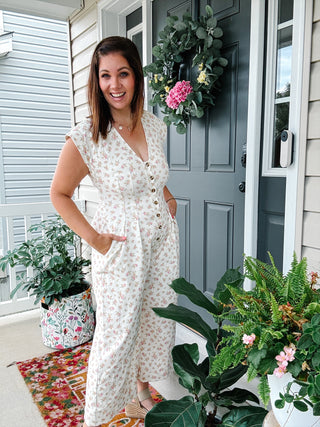 Woman wearing the Aurora floral wide leg jumpsuit featuring a vintage floral print, button front, V-neckline, tailored bodice, and hidden side pockets.