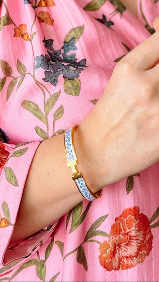 Person wearing a pink floral dress with a close-up of their hand and bracelet.