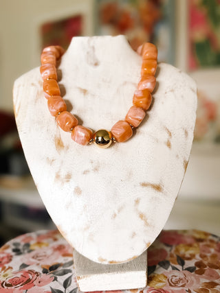 Blush pink chunky statement beaded necklace featuring oversized peach and pink marbled beads with a polished gold-tone center accent.