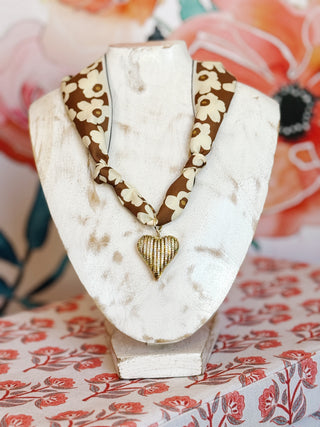 flay lay style photo with a brown scarf with bold boho retro cream floral with a gold plated crystal ribbed heart pendant