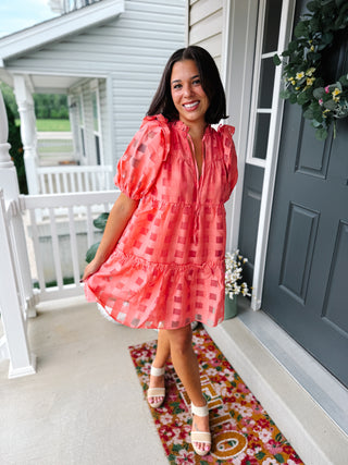 Woman wearing the Buddy Love coral textured mini dress featuring burnout fabric, puff sleeves, a ruffle neckline, tiered silhouette, and a relaxed fit perfect for vacations, brunch, and bridal showers.