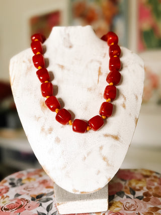 Burnt orange chunky statement necklace with glossy oversized reddish-orange beads and contrasting golden yellow knotted spacers.