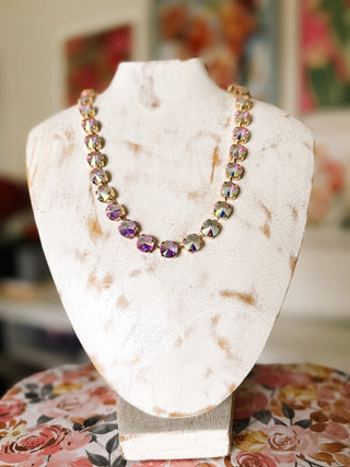 Champagne faceted stone statement necklace featuring graduated round iridescent stones with pink and lavender reflections in gold-tone prong settings.