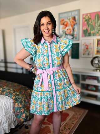 woman in teal, yellow and pink floral dress in a colorful roomf