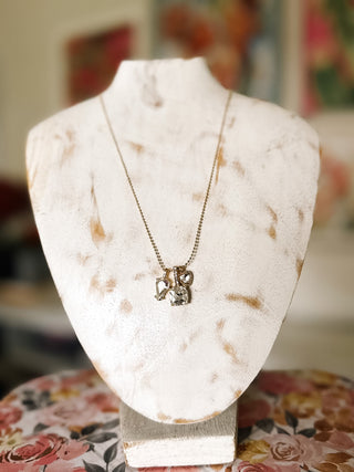 Antique gold-tone chain necklace featuring three clear faceted stone pendants in assorted shapes, displayed on an ivory jewelry bust.