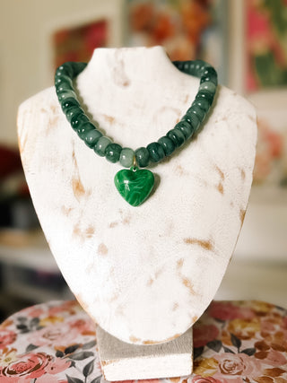 Chunky green beaded statement necklace featuring glossy marbled beads in forest and sage green with a large emerald green heart pendant.