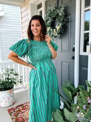 Women’s green striped midi dress with smocked bodice, detachable tie-on puff sleeves, peekaboo shoulders and pockets.