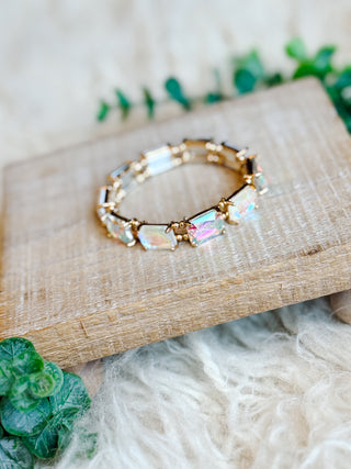 Bracelet with colorful beads on a wooden surface with greenery