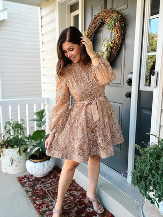Layla Lace Mini Dress in taupe with champagne floral embroidery, long balloon sleeves, covered buttons, a tie waist, and flared mini skirt.