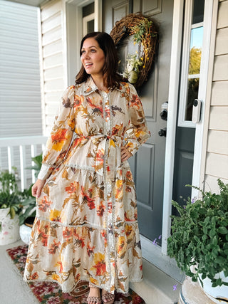 Marietta Maxi Dress in ivory with orange, rust, and yellow fall florals, collared neckline, decorative button front, tie waist, and tiered maxi skirt.