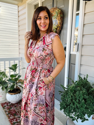 Woman wearing the Tilly pink floral midi dress with a zip front, smocked waist, sleeveless design, and brown knee-high boots.