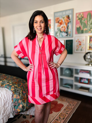 Woman wearing a red and pink striped dress in a room with floral decor.
