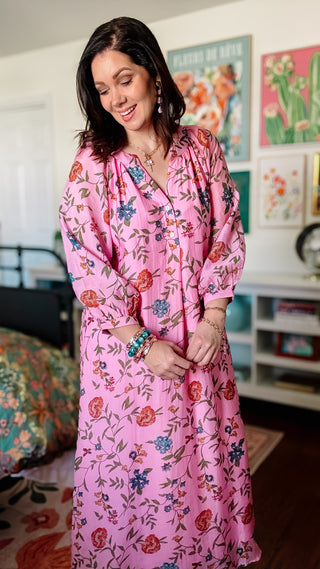 Woman wearing a pink floral dress in a room with colorful decor