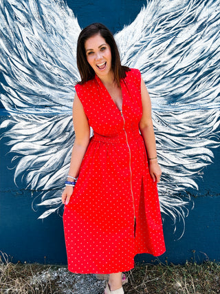 Red polka dot midi dress featuring a gold zip front, smocked waist, pockets, and a flattering fit. Perfect for Fourth of July celebrations, summer parties, and everyday wear.