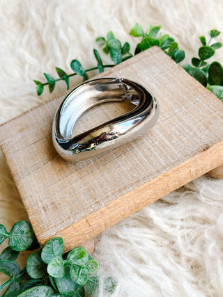 Silver bracelet on a wooden board with green leaves