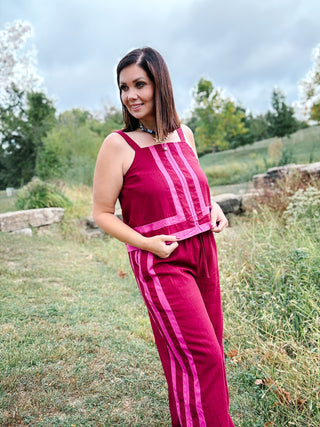 woman wearing tank and pants set in deep burgundy red with sporty pink stripe detail