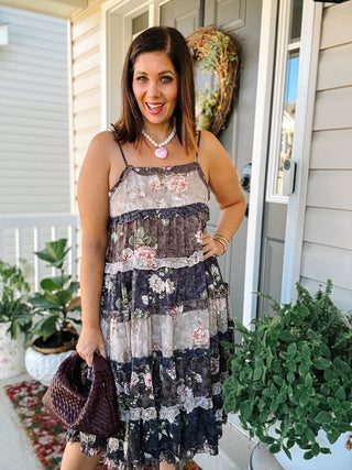 Woman wearing the Opal vintage floral tiered midi dress with adjustable spaghetti straps, patchwork-inspired pink and brown florals, and cascading ruffles.